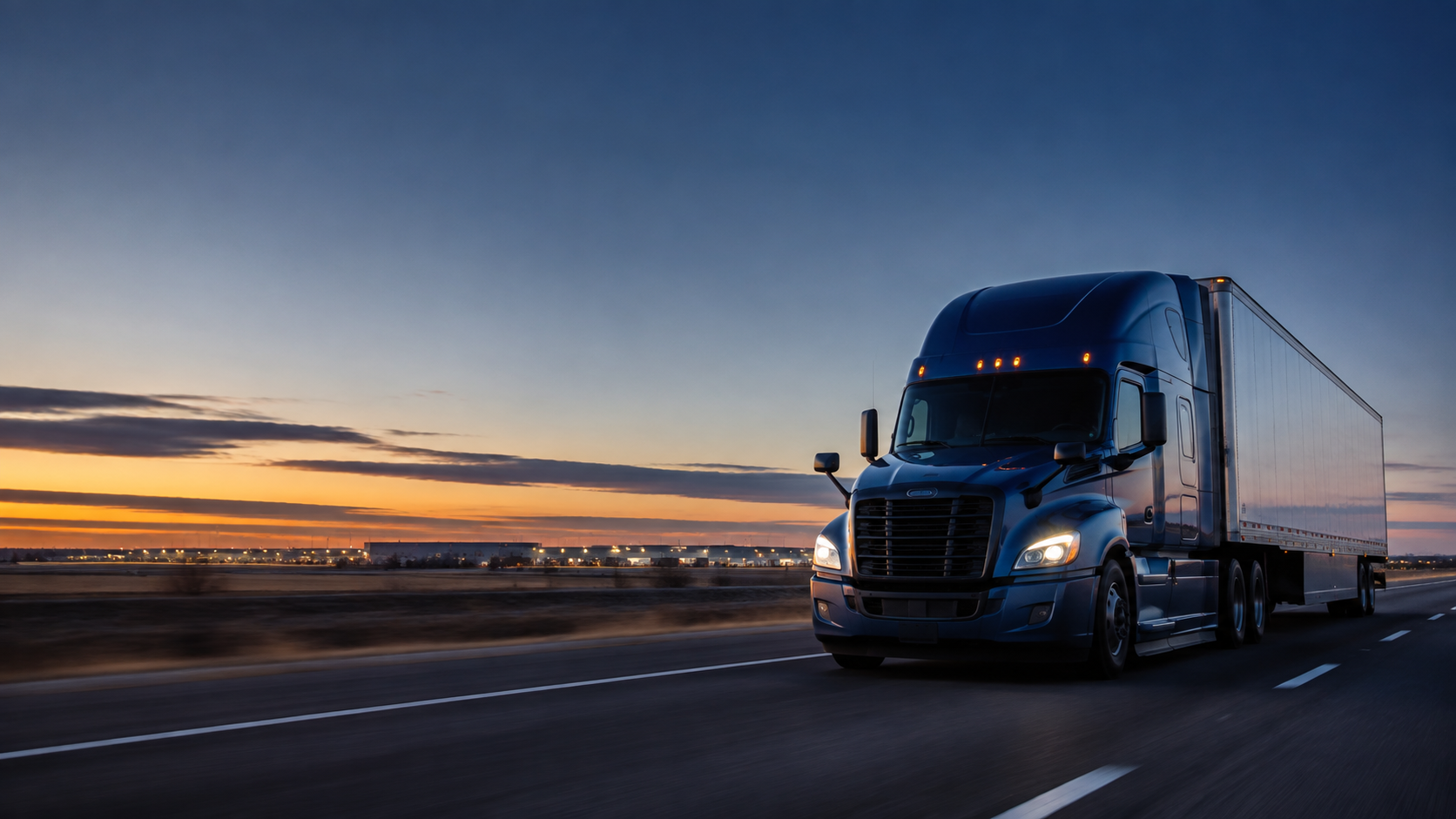 A modern semi-truck moving along a Midwestern highway at blue hour